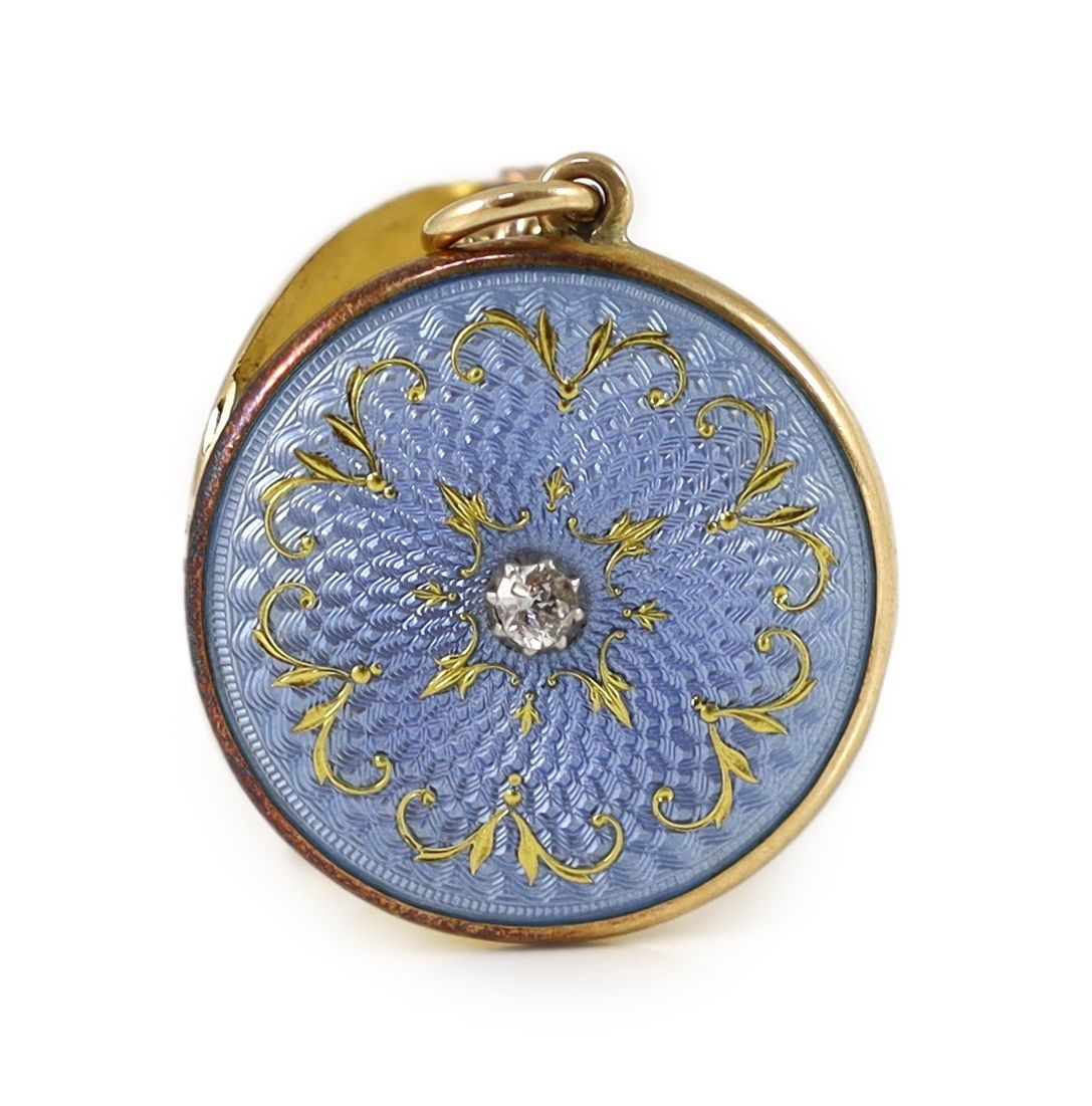 An Edwardian engine turned gold, blue guilloche enamel with gilded scrolls and diamond set circular pendant locket